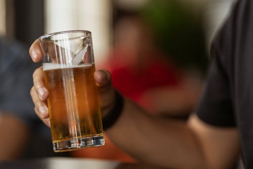 A Person Holding a Clear Drinking Glass with Beer