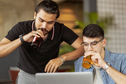 Men Drinking Beer and Looking at a Laptop Screen 