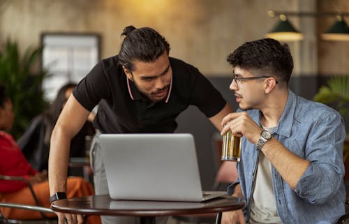Two Men Looking at Laptop and Having Beer in Bar 