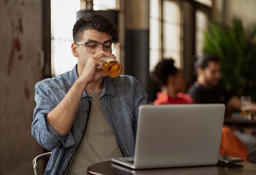 Man with Laptop and Beer in Bar