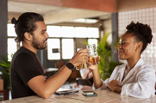 Free Two friends happily share a toast with beer inside a cozy bar setting. Stock Photo