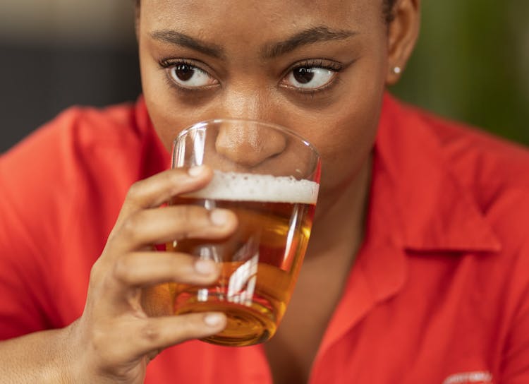 Close Up Photo Of Woman In Red Dress Shirt Drinking A Glass Of Beer