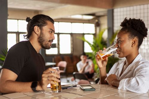 Free Two adults enjoying drinks and conversation in a relaxed bar setting. Stock Photo