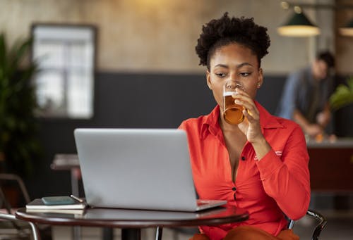 Woman Drinking and Looking at Laptop