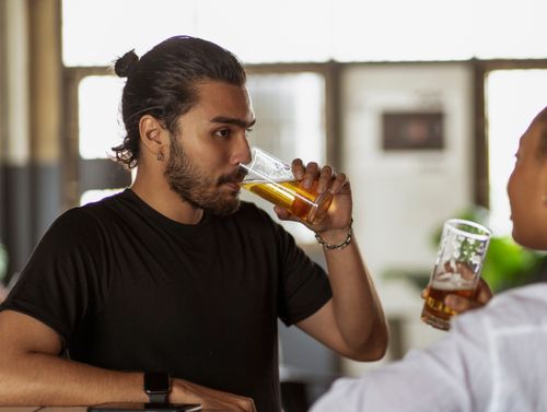 Free A young man enjoying a drink in a contemporary bar environment, engaging in leisure activities. Stock Photo