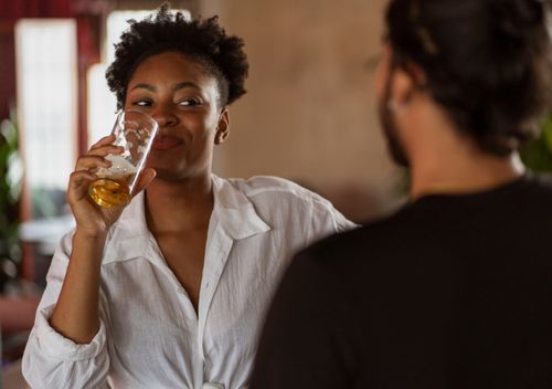 Free Two adults engaged in a friendly conversation while enjoying a drink indoors. Stock Photo