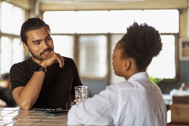Two people talking across a table indoors. Photo by Ketut Subiyanto on Pexels