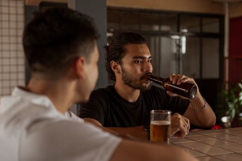 Free Two men enjoying drinks at a cozy indoor bar setting, capturing a relaxed social vibe. Stock Photo