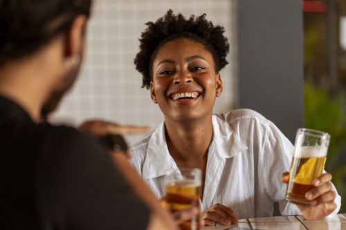 Free Two friends laughing and enjoying beer at an indoor social gathering. Stock Photo