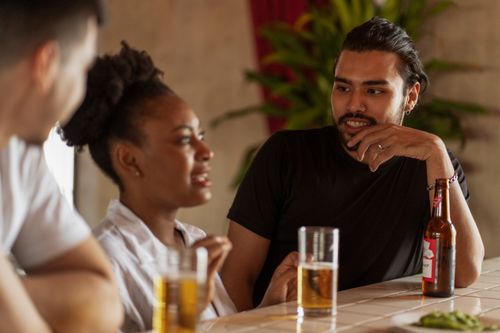 Free Group of friends socializing over drinks indoors, capturing a relaxed and warm atmosphere. Stock Photo