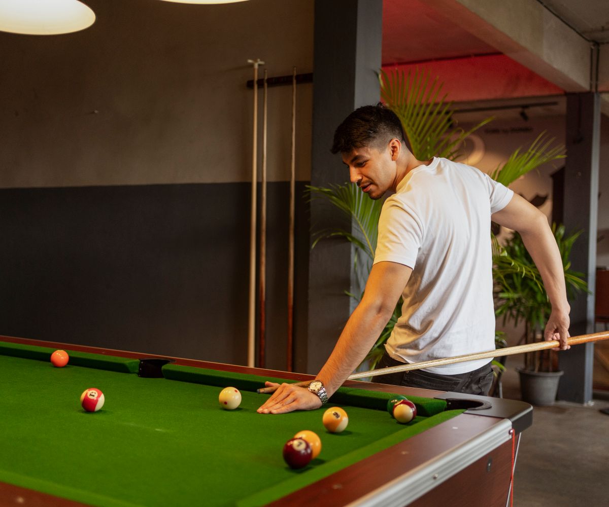 Young man focused while playing snooker on a professional green slate table