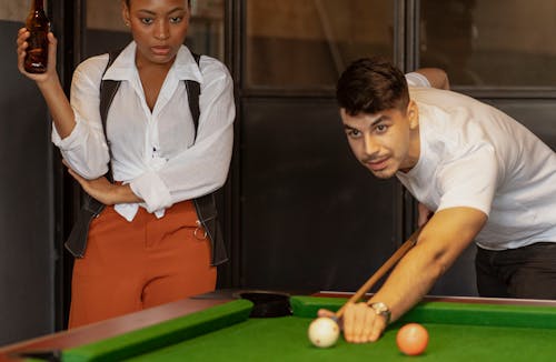 Two People Playing Pool and Having Beer 