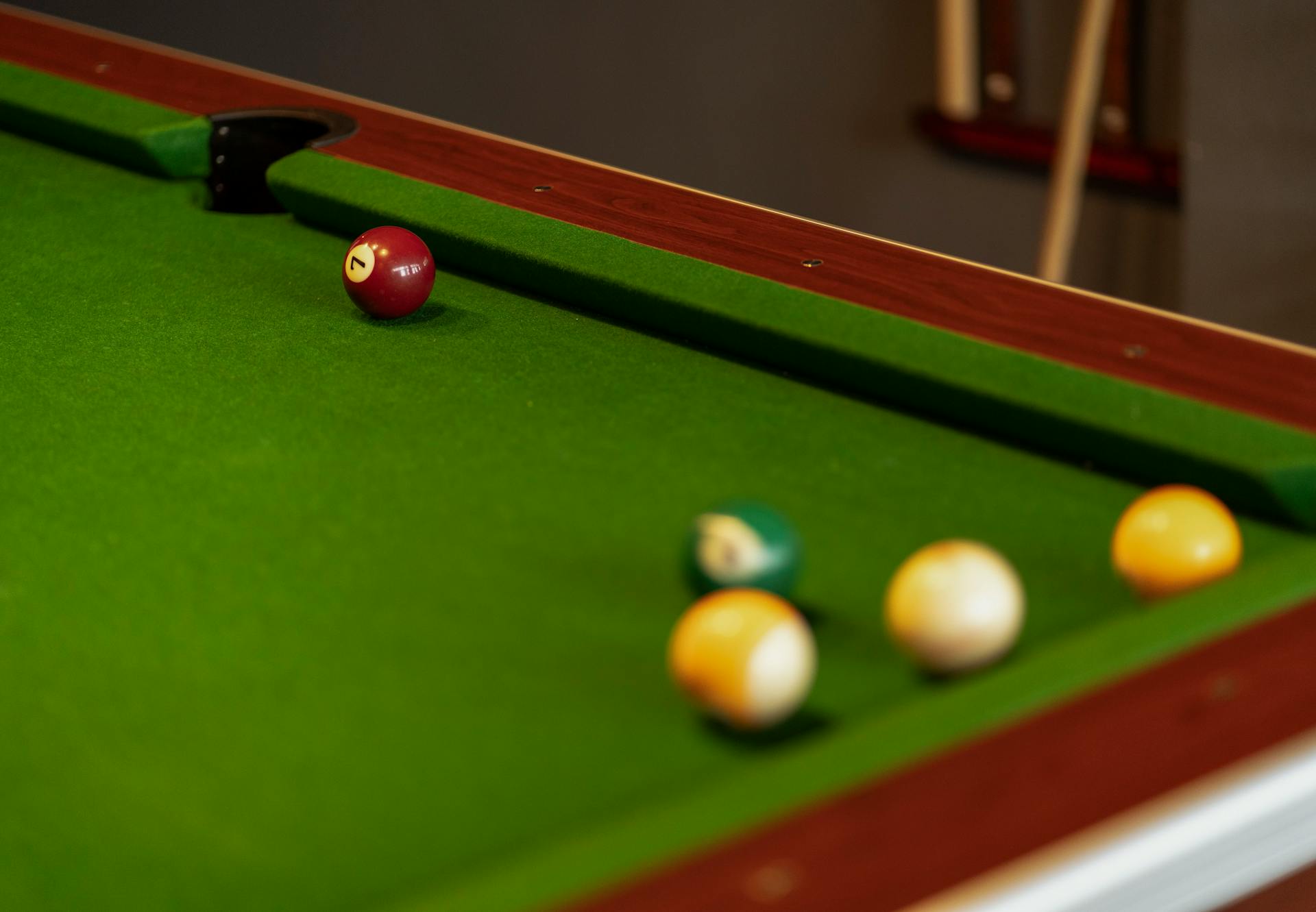 A close-up view of billiard balls on a green snooker table, showcasing a number 7 ball.