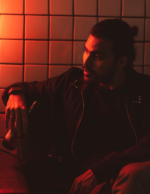 Free A dramatic portrait of a man sitting indoors, illuminated by red lighting. Stock Photo