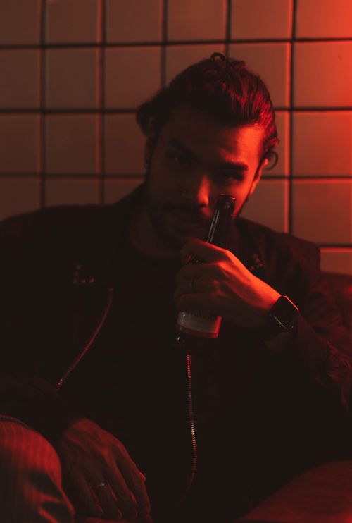 Free A man in a dimly lit bar enjoying a drink in ambient red lighting. Perfect for nightlife themes. Stock Photo