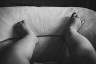 Grayscale Photo of Persons Feet on White Textile