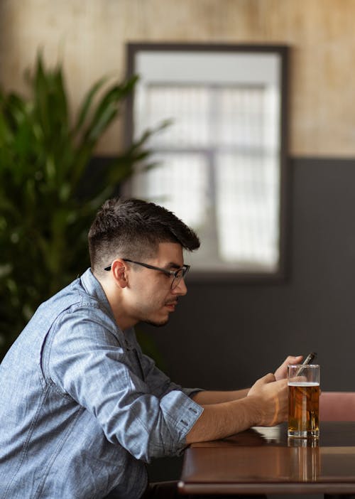 A Man Sitting at the Bar with a Phone