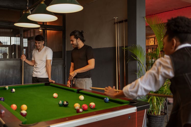 Friends Playing Billiards In Club