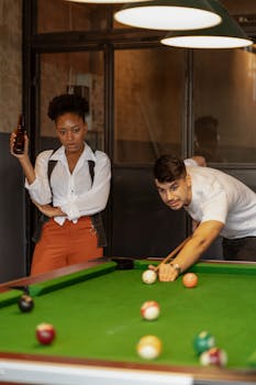 A woman and man enjoy a game of billiards indoors. Vibrant and social.