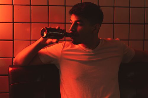 Free A man enjoying a beer in a warm, intimate indoor environment with soft lighting. Stock Photo