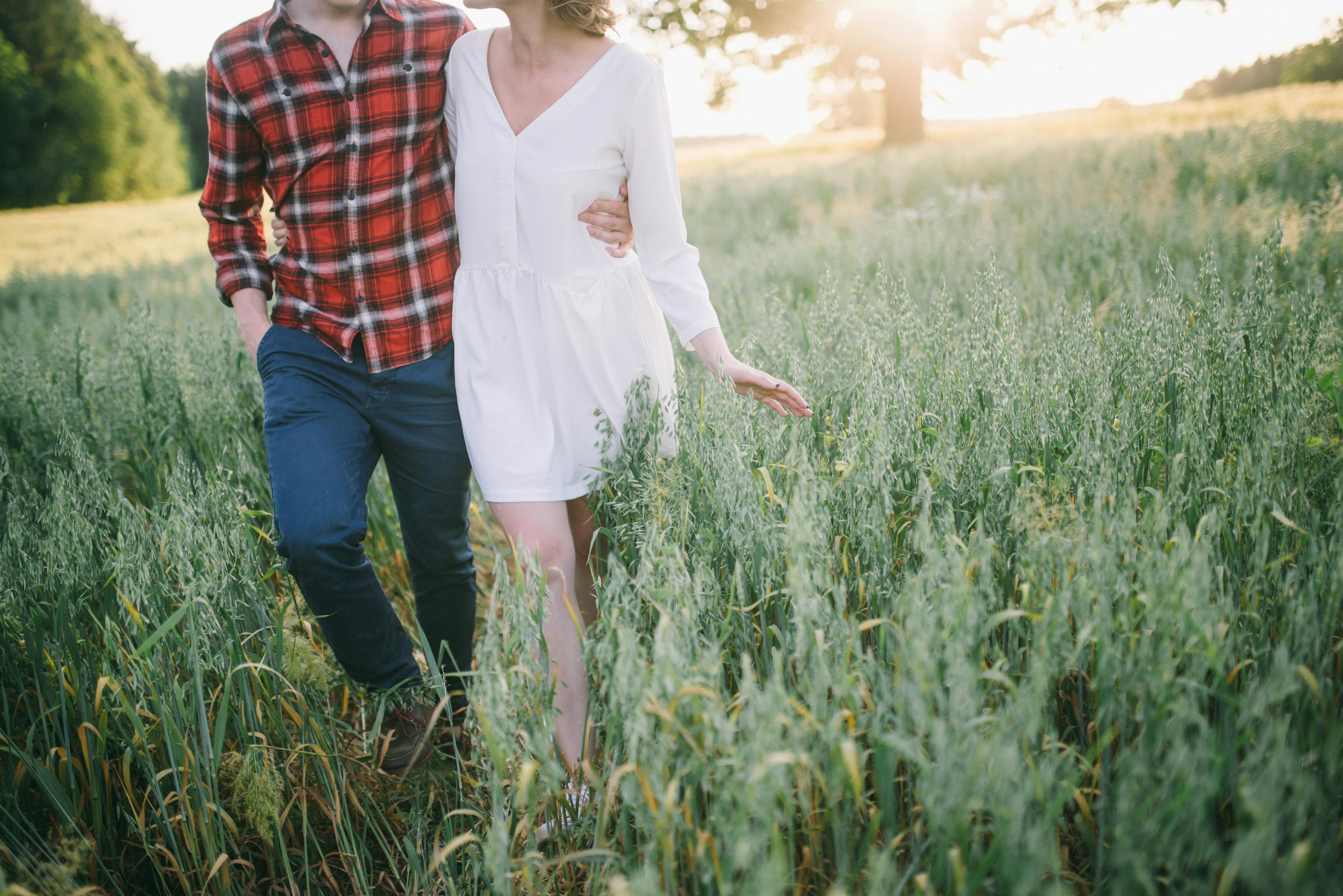 一对夫妇在阳光明媚的草地上漫步，享受着温暖的夏日，表达着爱意