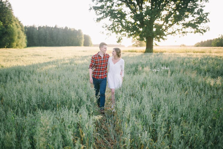 A Man And A Woman Walking In The Farm Field