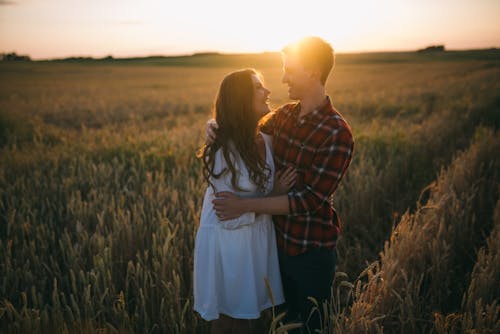 Couple Hugging and Looking at Each Other on a Field at Sunset 