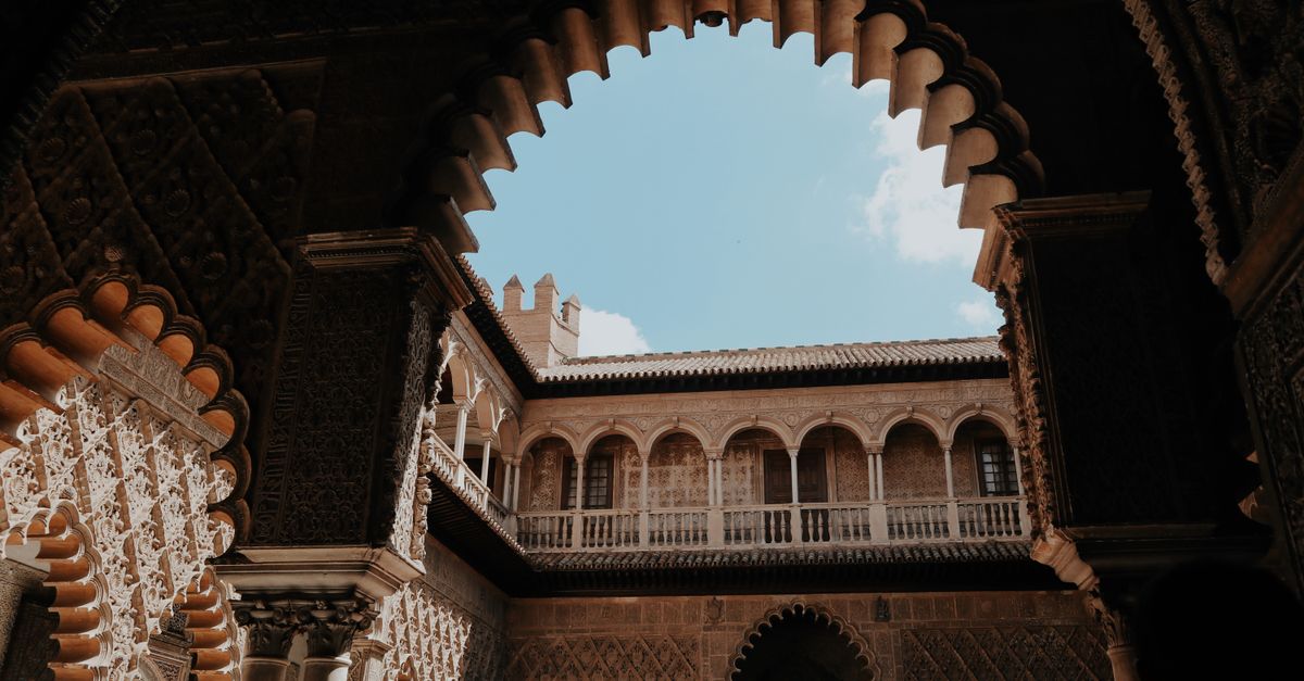 Stunning view of moorish arches and courtyard in Seville, Spain, showcasing intricate architectural detail.