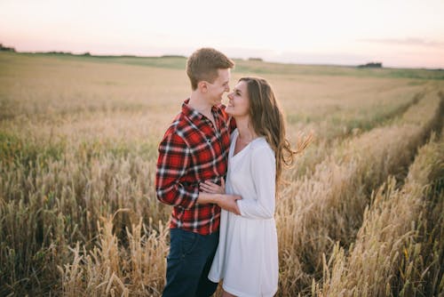 Free Man and Woman Holding Hands on the Grass Field Stock Photo
