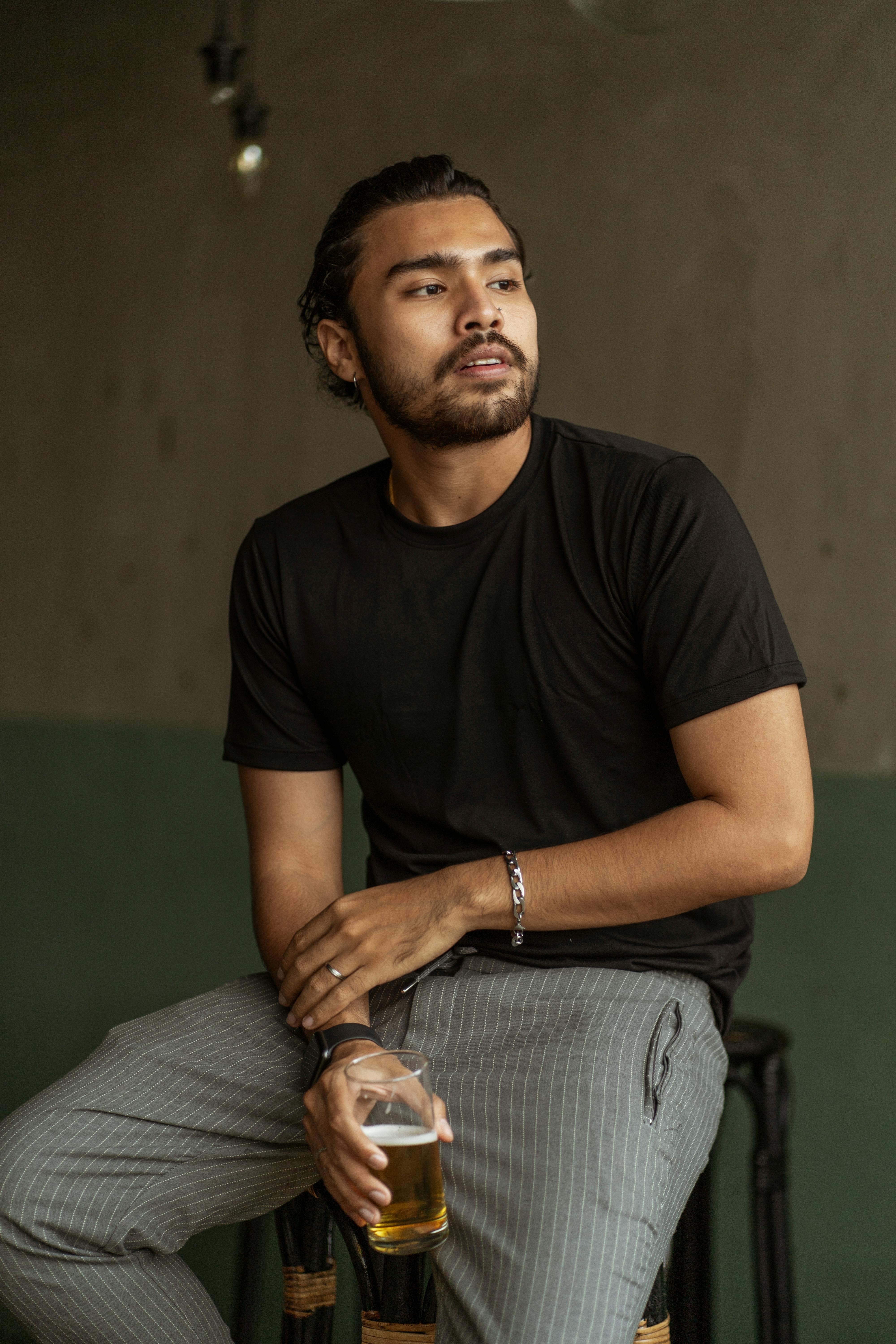 Man in Black Crew Neck T-shirt and Gray Denim Jeans Sitting on Green Couch