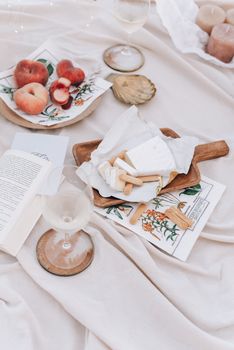 柔软的毯子上，美食野餐的布置奠定了葡萄酒、奶酪和桃子的时尚平面