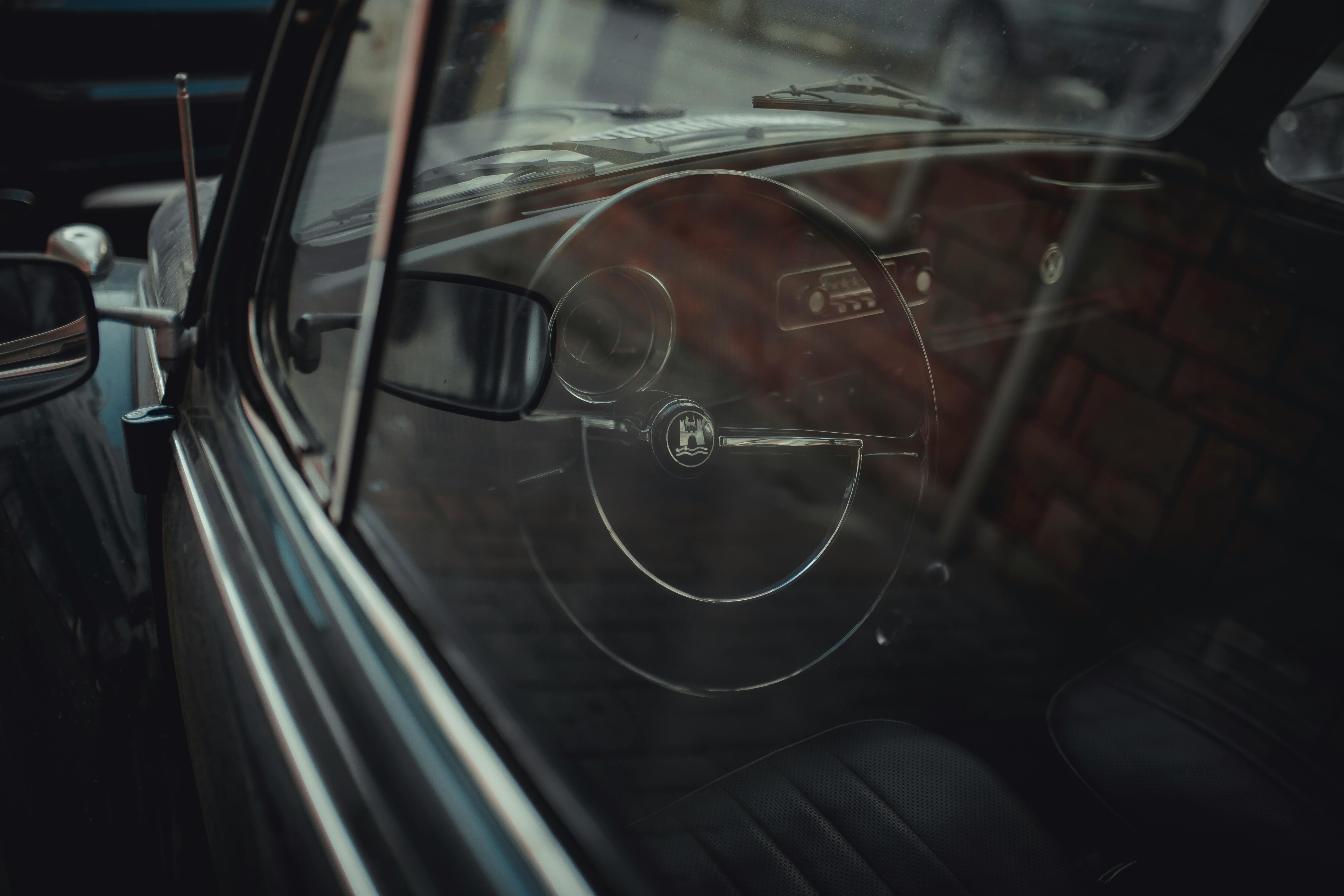 A vintage car interior showing the iconic steering wheel through the window, capturing nostalgia.