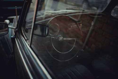 Free A vintage car interior showing the iconic steering wheel through the window, capturing nostalgia. Stock Photo