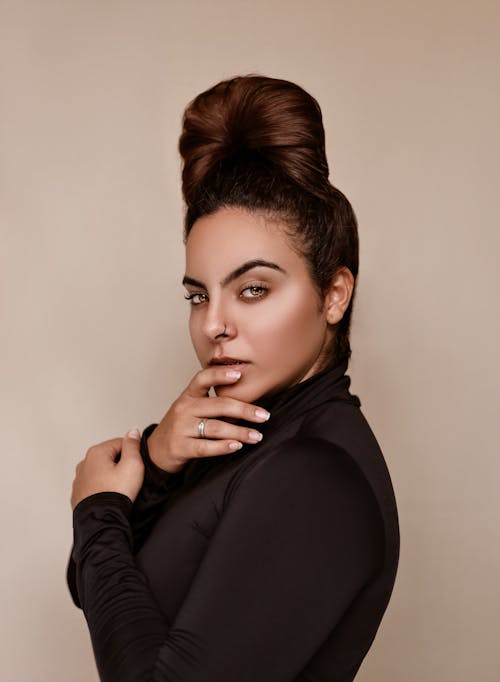 Fashionable woman standing near beige wall