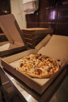 餐桌上打开的外卖盒里，有一份配料丰富的热披萨