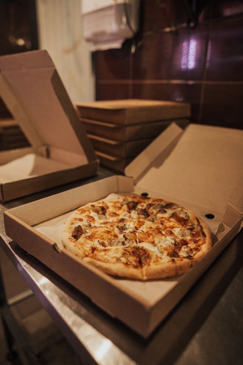 Free Delicious hot pizza with toppings in an open takeout box on a restaurant table. Stock Photo