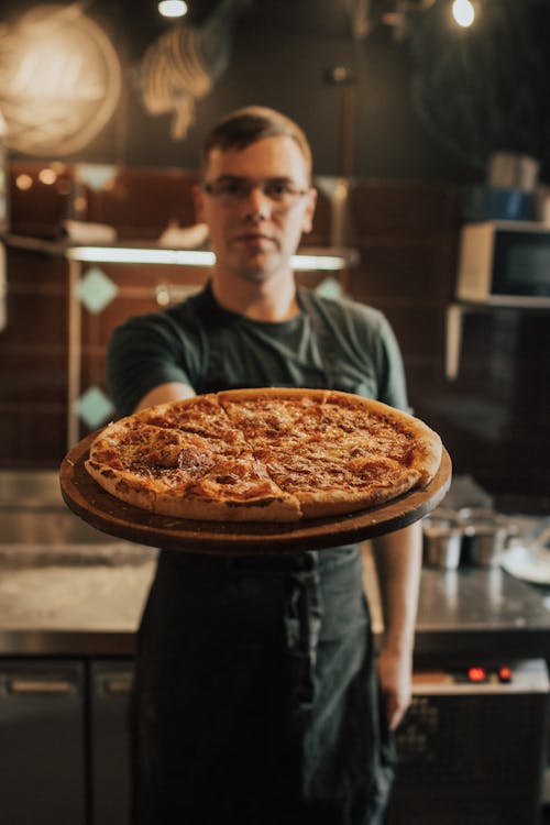 A Man in Black Shirt Holding a Pizza