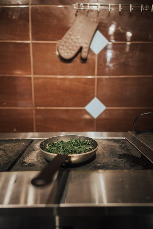 A Frying Pan with Spinach Standing on the Stove