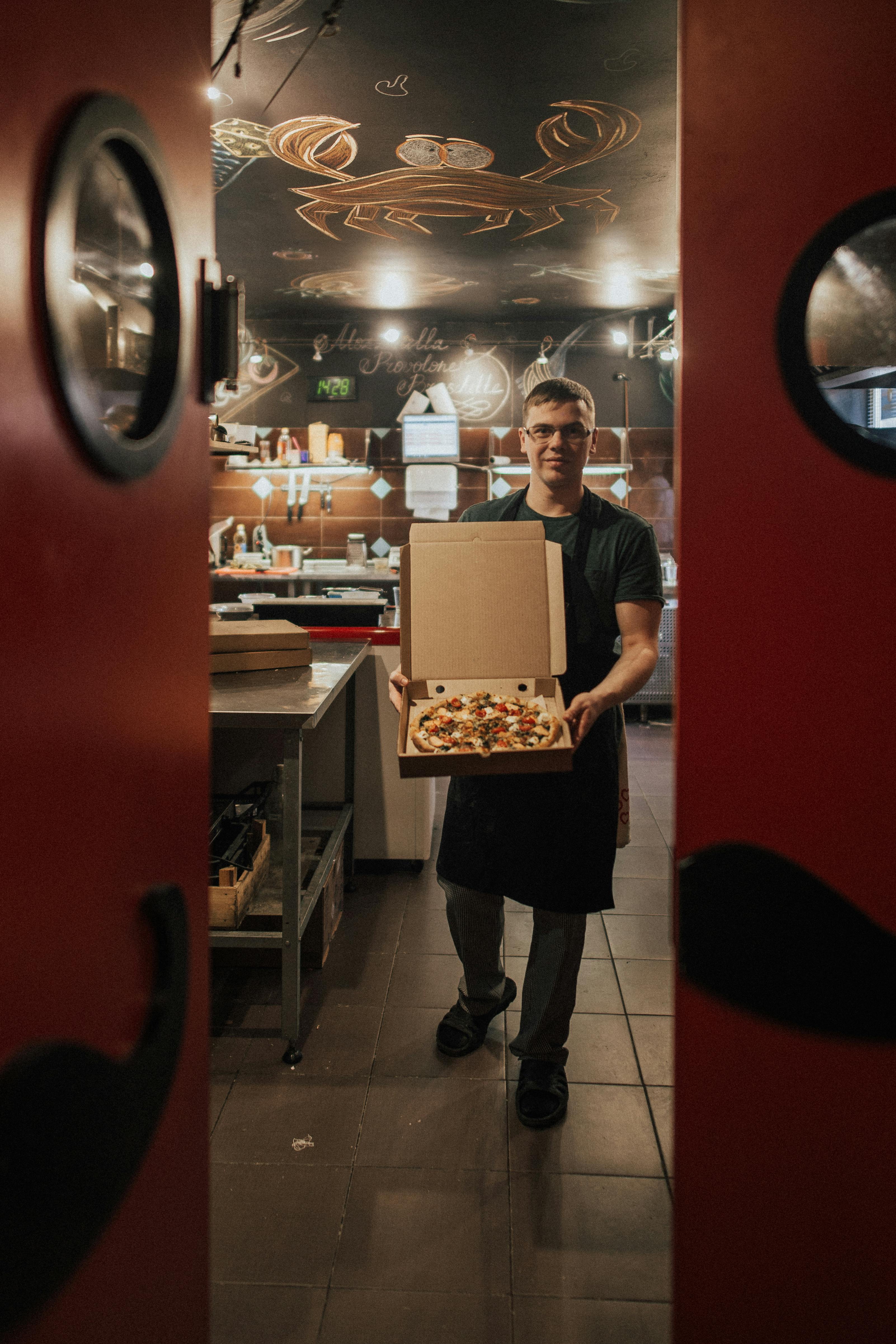 male chef holding a pizza box open Stock Photo