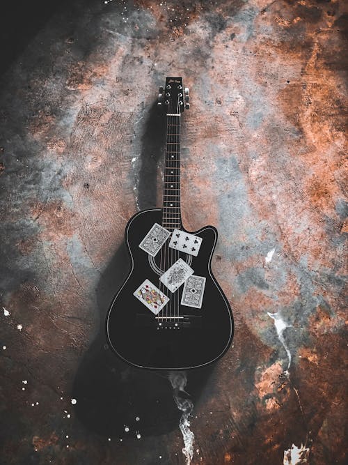 Black Acoustic Guitar on Concrete Surface