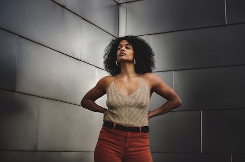 Free Self assured ethnic woman with Afro hair standing near shiny gray wall Stock Photo