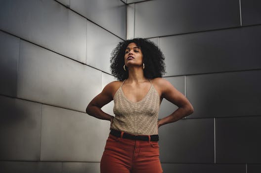 Stylish woman with curly hair posing indoors, showcasing confidence and modern fashion.