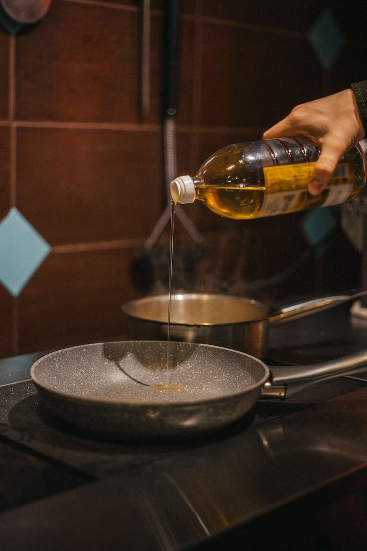 Person Pouring Cooking Oil In A Pan