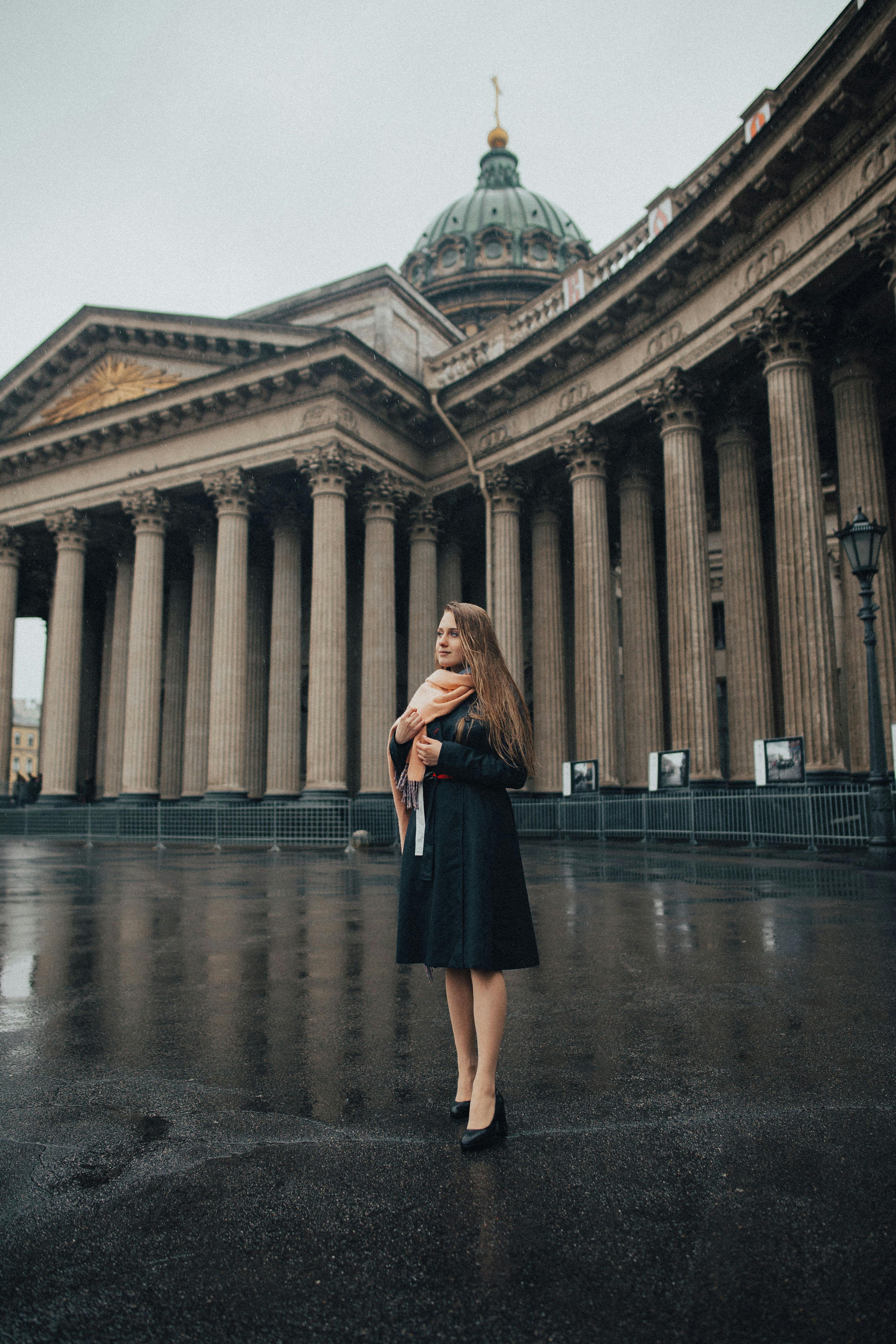 阴天，一名围着围巾、身着黑色连衣裙的女士，站在标志性的喀山大教堂前