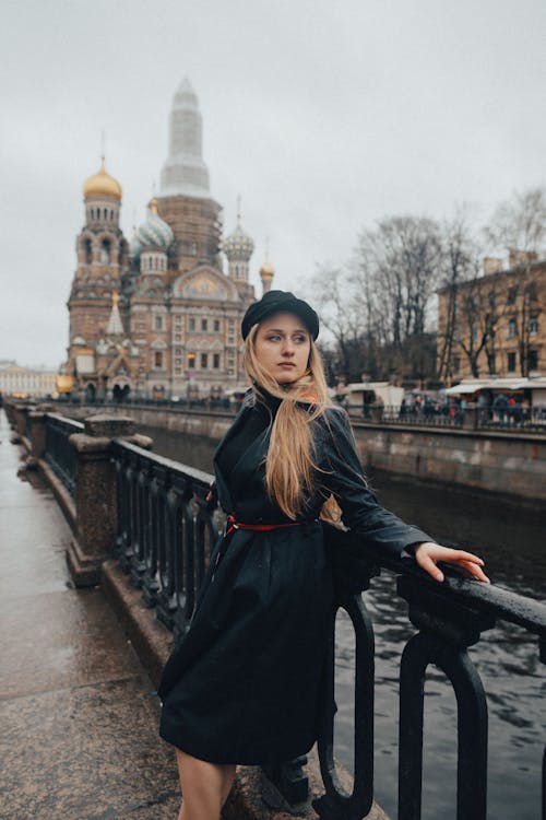 Young Woman Standing by the Canal on the Background of the Church of the Savior on Spilled Blood in Saint Petersburg, Russia