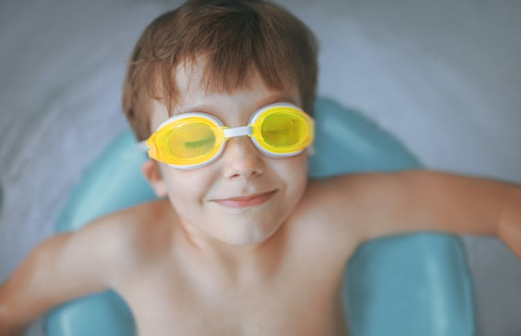 Cheerful Child Swimming In Pool With Rubber Ring