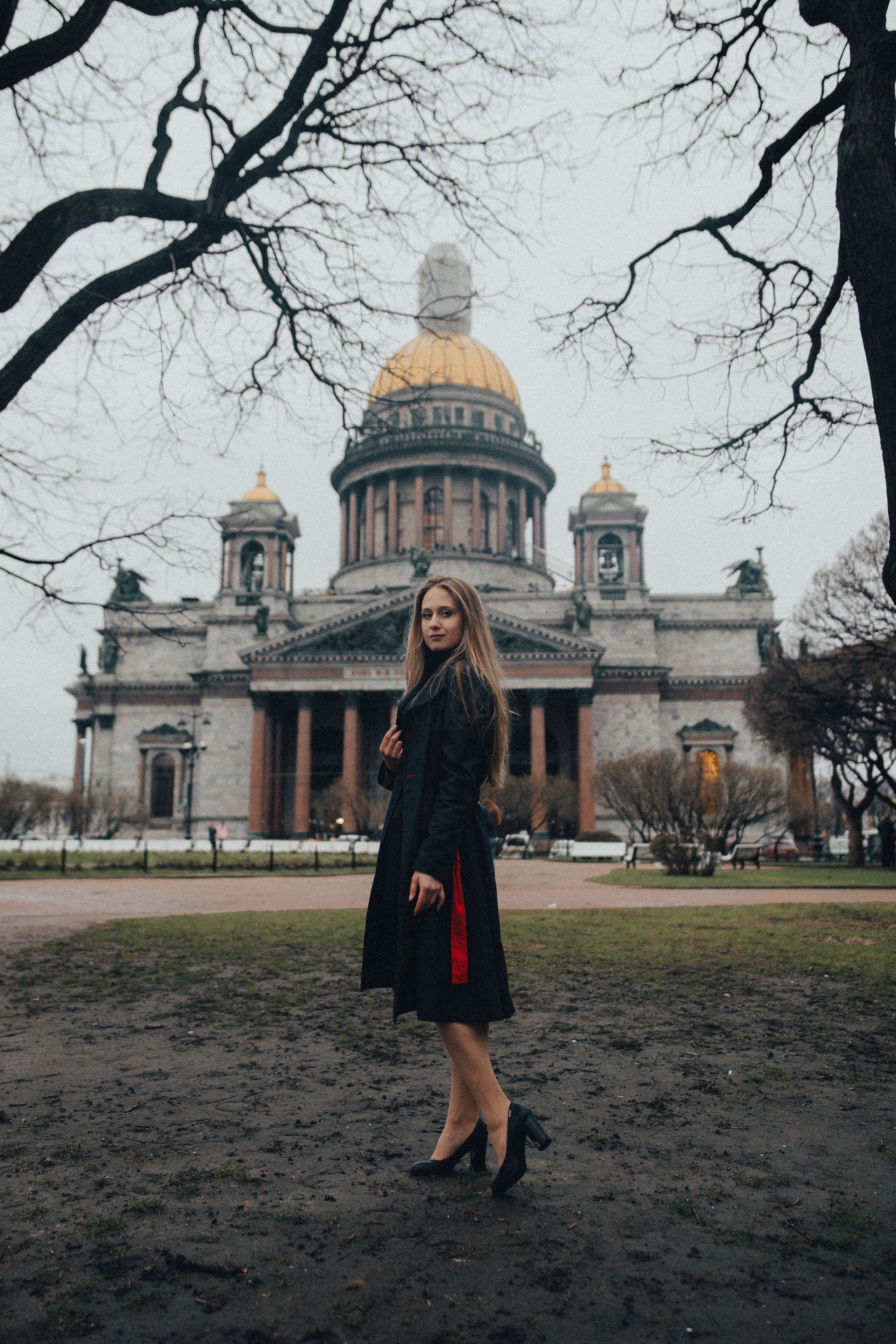 Woman in Black Coat Standing beside a Concrete Building · Free Stock Photo