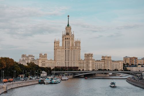 Free View of a Stalinist skyscraper by the Moscow River with boats and a bridge. Stock Photo