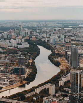 从空中俯瞰，城市的壮丽景象令人惊叹，庞大的建筑群与蜿蜒的河流在多云的天空下勾勒出美丽的天际线