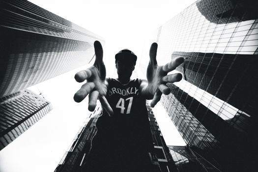 黑白图像中，一个人正从摩天大楼里伸出援手